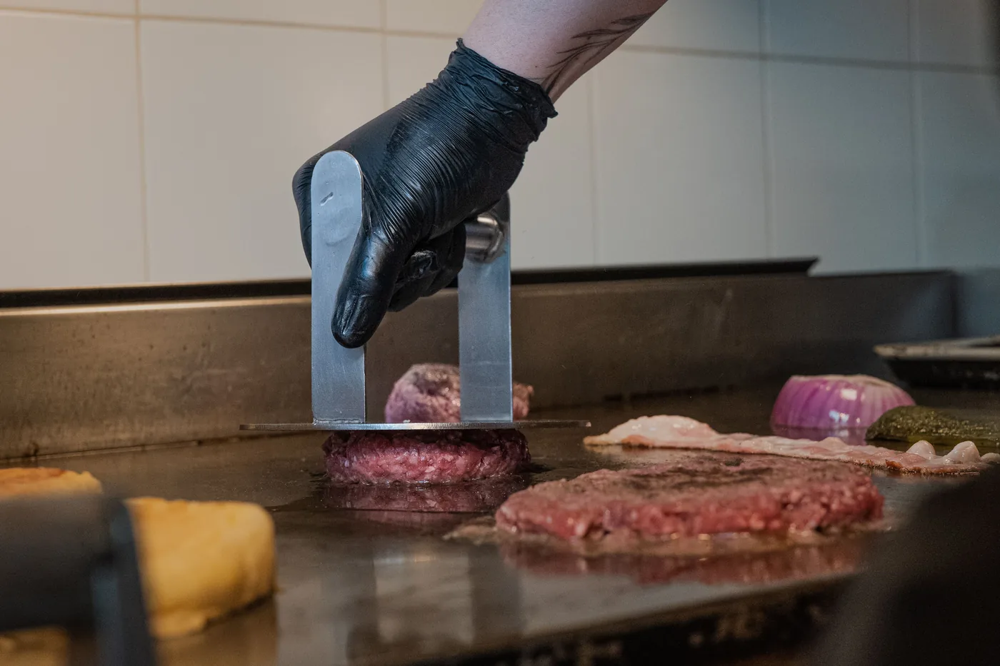 Burger patties being prepared on a hot restaurant grill
